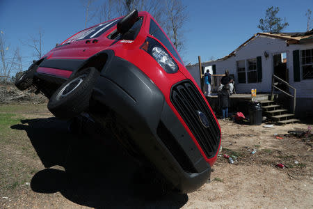 A truck sits overturned as the Baker family sits on the porch of their destroyed home after two deadly back-to-back tornadoes, in Beauregard, Alabama, U.S., March 6, 2019. REUTERS/Shannon Stapleton