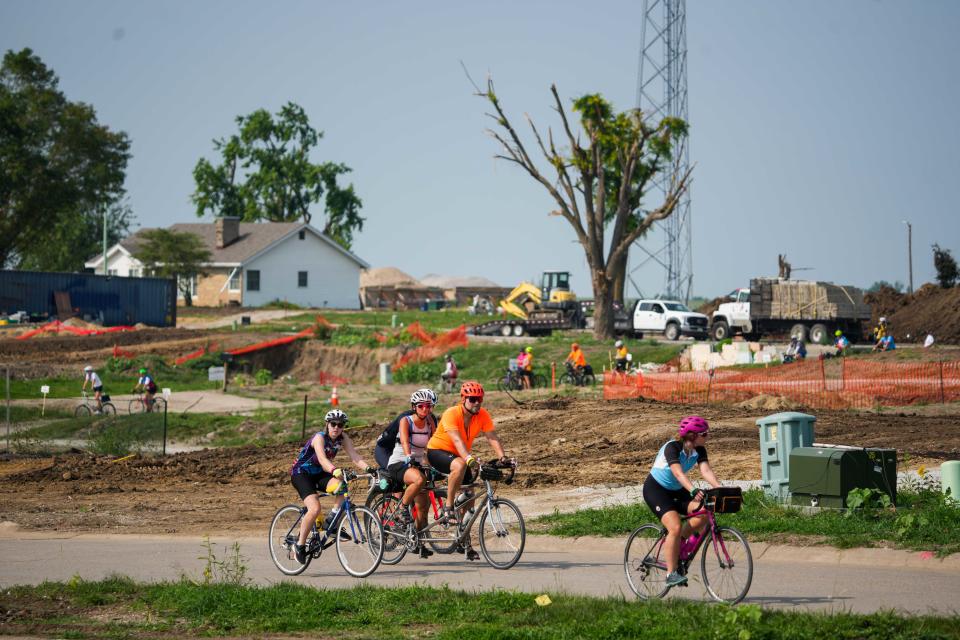 RAGBRAI riders make their way past the aftermath of an EF4 tornado that hit Greenfield in May as they stop on Day 3 of RAGBRAI 2024 on Tuesday, July 23, 2024, in Greenfield, IA.