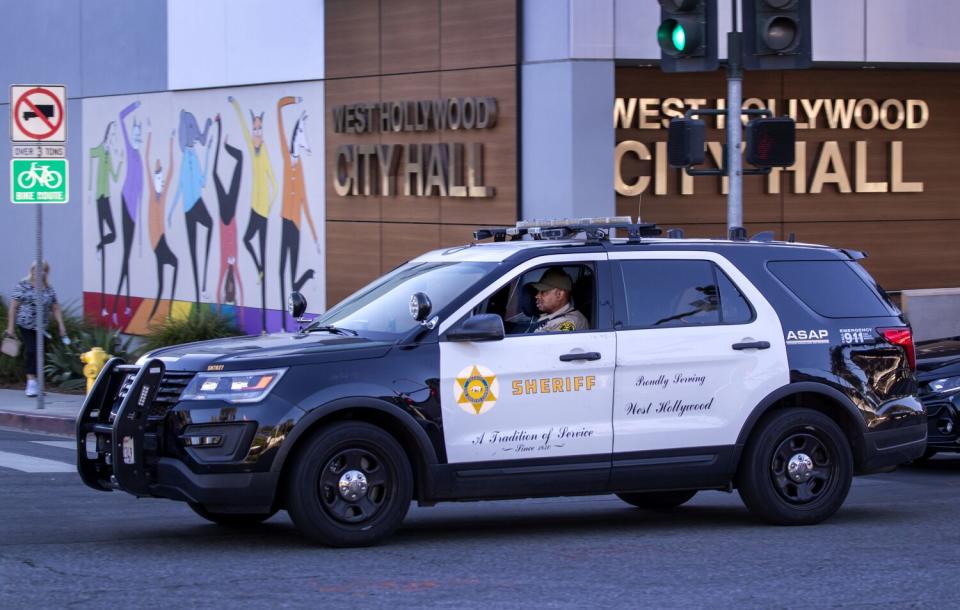 A Los Angeles County sheriff's deputy drives past West Hollywood City Hall