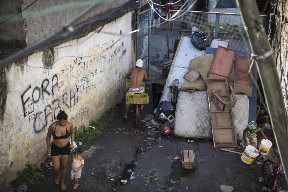 In this Jan. 9, 2014 photo, residents walk inside the Favela do Metro slum near Maracana stadium where people have been evicted and homes demolished in Rio de Janeiro, Brazil. The evictions and demolitions in this slum are part of urban renewal efforts launched ahead of this year’s World Cup and the 2016 Olympics. (AP Photo/Felipe Dana)