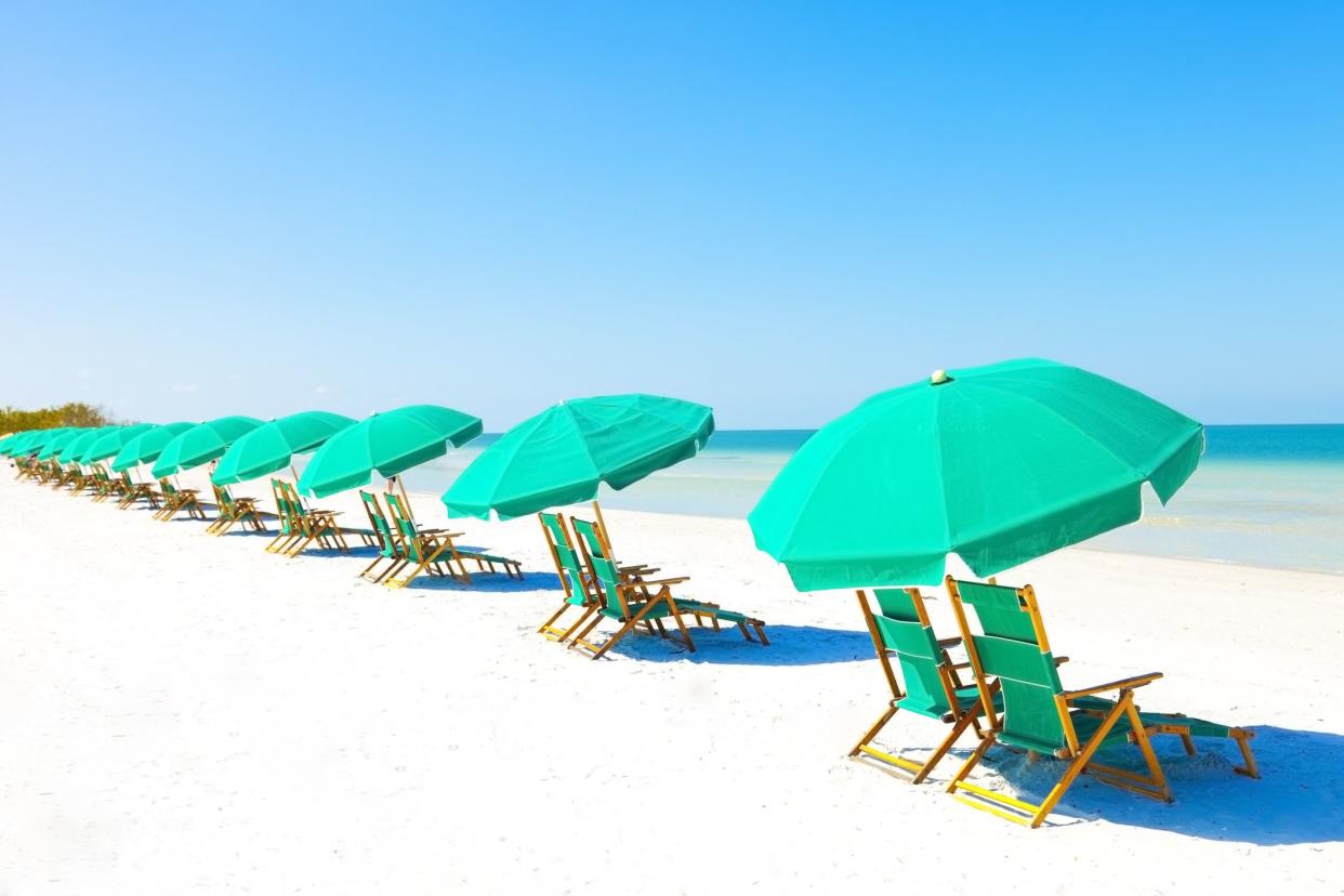 Green beach loungers and umbrellas at white sandy beach