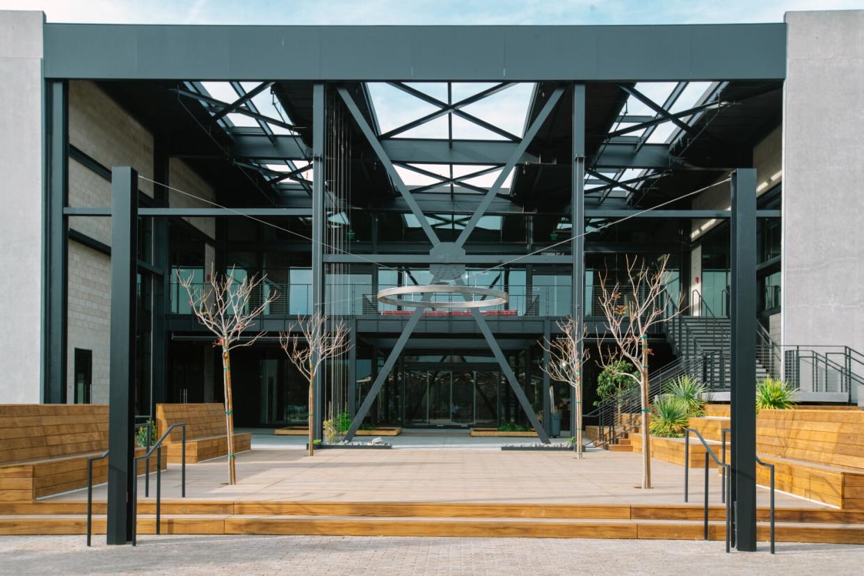 A view of the Press shows a building entrance framed by black steel beams, one in the shape of an X