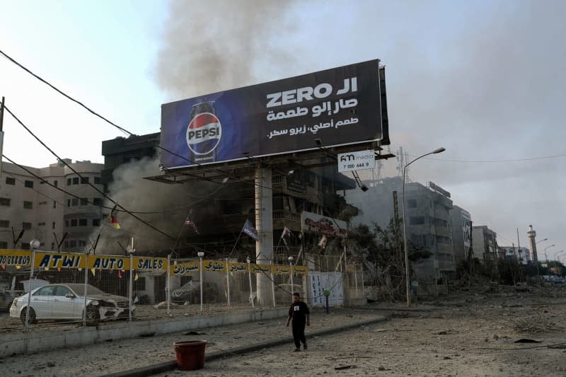 A man walks past buildings targeted by Israeli airstrikes on Beirut's old airport road on the edge of Beirut's southern suburbs. Stringer/dpa