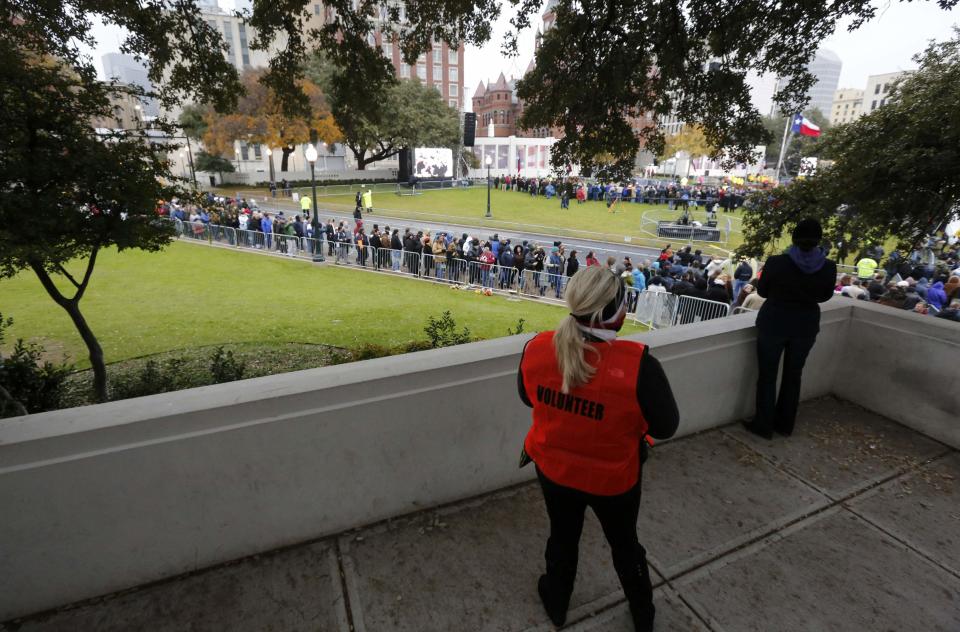 An event volunteer and a spectator look down on Dealey Plaza's "grassy knoll" prior to 50th anniversary ceremonies of JFK's assassination in Dallas