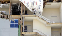 FILE - In this Sept. 2, 2017, file photo, workers pick up debris in a staircase of a four-story hotel exposed when the wall fell during Hurricane Harvey, in Rockport, Texas. While it could take a decade to fully recover from Harvey, which came ashore Aug. 25, 2017, as a Category 4 storm, officials say Texas has already made great strides. However, they acknowledge that federal recovery funding has been slow in coming for some residents and that many are feeling frustrated and forgotten. (AP Photo/Eric Gay, File)