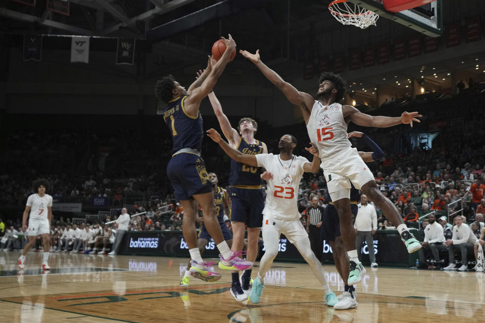 Notre Dame guard Julian Roper II (1) gathers in a rebound over Miami forward Norchad Omier (15) during the first half of an NCAA college basketball game, Saturday, Dec. 2, 2023, in Coral Gables, Fla. (AP Photo/Jim Rassol)
