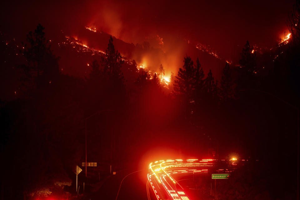 Fire trucks pass the Delta Fire burning in the Shasta-Trinity National Forest, Calif., on Wednesday, Sept. 5, 2018. Parked trucks lined more than two miles of Interstate 5 as both directions remained closed to traffic. (AP Photo/Noah Berger)