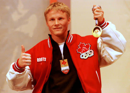 FILE PHOTO: Canadian snowboarder Ross Rebagliati holds his Olympic snowboarding giant slalom gold medal February 13 during a news conference. The international sports arbitration panel announced his Olympic disqualification had been reversed and he could keep his gold medal. /File Photo