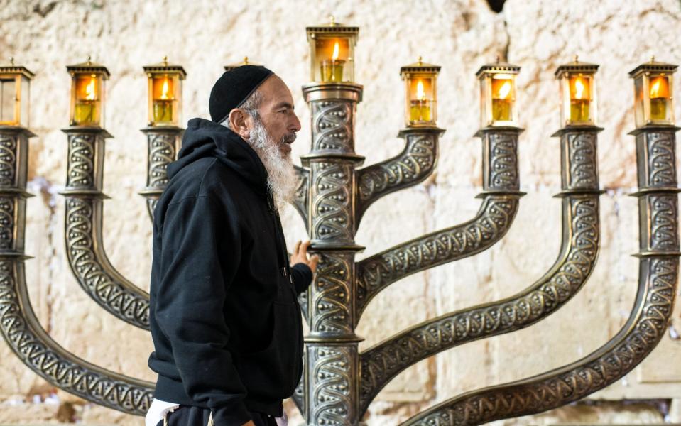 A man next to a menorah at the Western Wall in Jerusalem on the seventh day of Hanukkah - REX