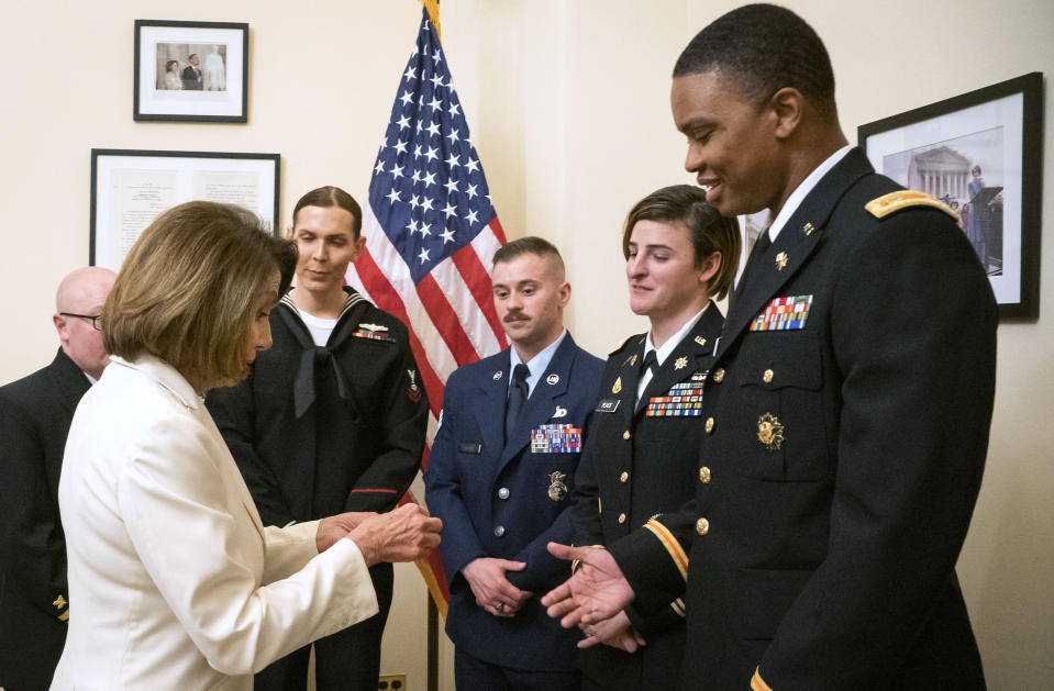 In this Tuesday, Feb. 5, 2019 photo released by the her office, Speaker of the House Nancy Pelosi, D-Calif., left, gives challenge coins to U.S. Army Maj. Ian Brown, right, and other military service members to thank them for their service, in her office at the Capitol following the State of the Union address in Washington. Brown, 38, is a two-time Bronze Star recipient who transitioned from female to male while advising the Army's deputy chief of staff in operations and planning. (Julio Obscura/Office of the Speaker of the House Nancy Pelosi via AP)