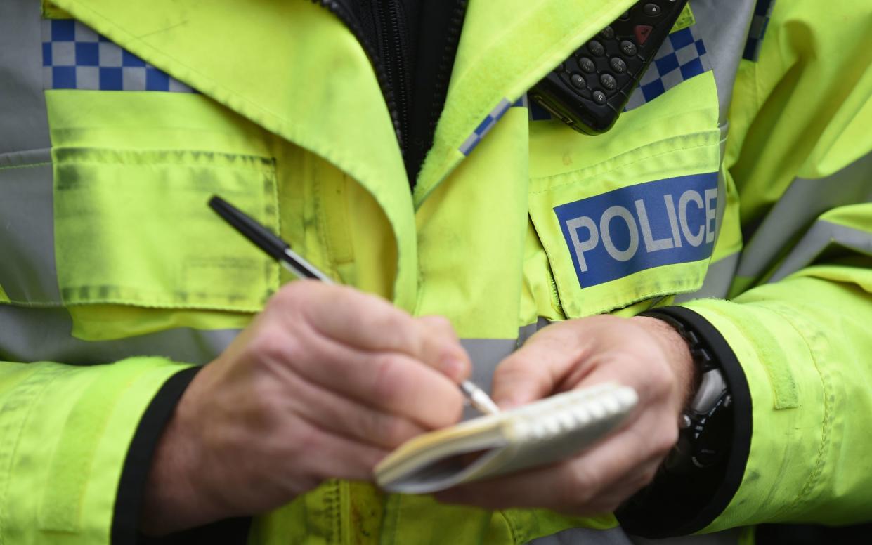 Police officer writing on paper - JOE GIDDENS