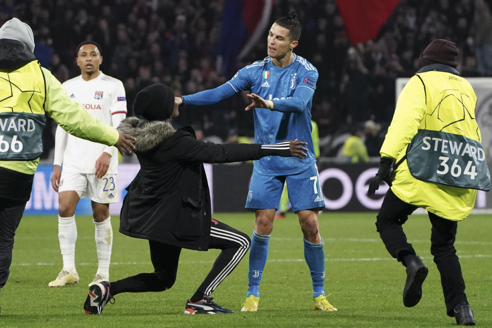 Un hincha se arrodilla ante Cristiano Ronaldo, de la Juventus, tras invadir la cancha durante el encuentro de la Liga de Campeones en cancha del Lyon, el miércoles 26 de febrero de 2020 (AP Foto/Laurent Cipriani)