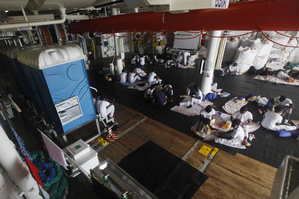 African migrants eat their lunch on the deck of the Geo Barents, a rescue vessel operated by MSF (Doctors Without Borders) off Libya, in the central Mediterranean route, Wednesday, Sept. 22, 2021. (AP Photo/Ahmed Hatem)