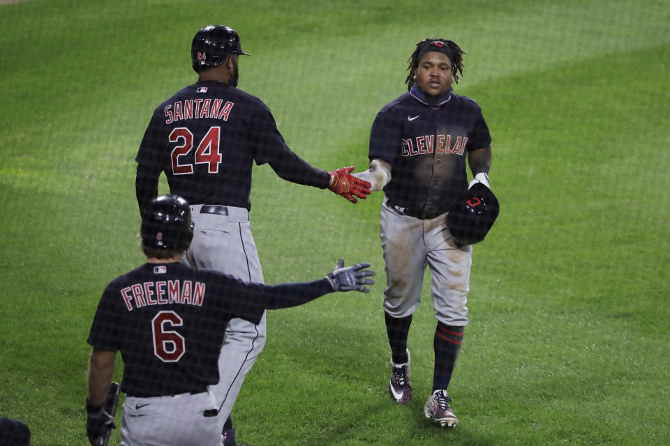 Cleveland Indians' Jose Ramirez, right, celebrates with Domingo Santana (24) and Mike Freeman after scoring on a sacrifice bunt by Delino DeShields during the 10th inning of the team's baseball game against the Chicago White Sox in Chicago, Sunday, Aug. 9, 2020. (AP Photo/Nam Y. Huh)