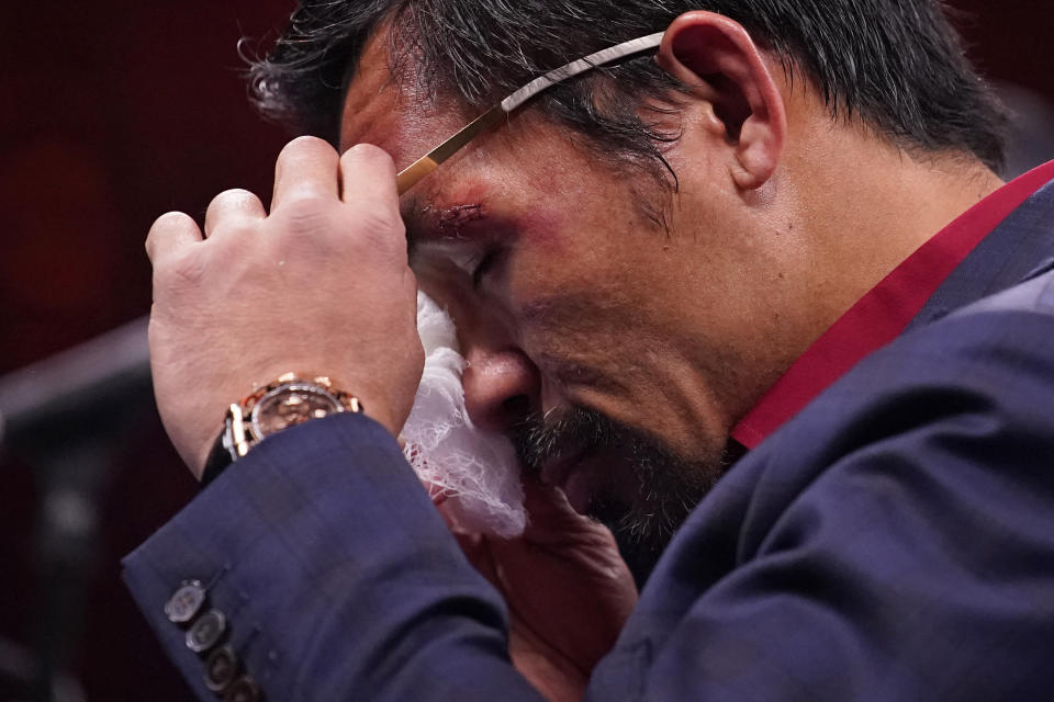 Manny Pacquiao, of the Philippines, wipes his eye at a news conference after his loss to Yordenis Ugas, of Cuba, in a welterweight championship boxing match Saturday, Aug. 21, 2021, in Las Vegas. (AP Photo/John Locher)