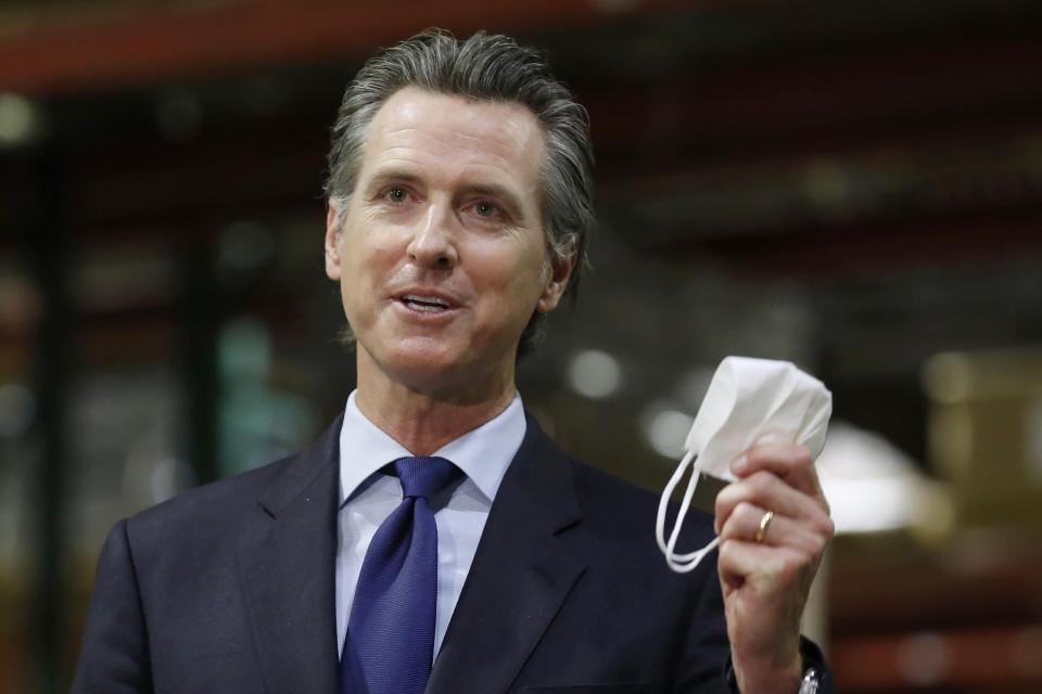California Gov. Gavin Newsom holds a face mask during a news conference in Rancho Cordova, Calif., in February 2022.