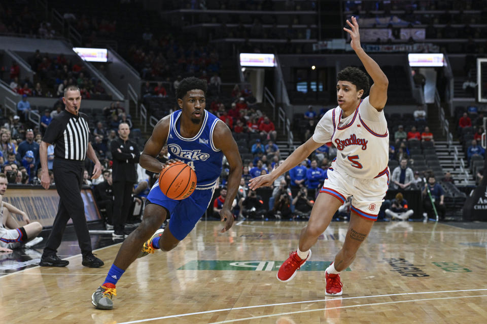 Drake Bulldogs guard Sardaar Calhoun, left, drives to the net as Bradley Braves guard Christian Davis (5) defends during the first half of the championship game in the MVC basketball tournament, Sunday, March 5, 2023, in St. Louis. (AP Photo/Joe Puetz)