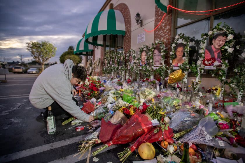 Monterey Park, CA - January 30: Mary Ma burns incense to honor her father, Wing Wei Ma, owner of the Star Ballroom Dance Studio, in front of his photo shown at right, among a growing memorial for the 11 mass shooting victims in front of the Star Ballroom Dance Studio in Monterey Park Monday, Jan. 30, 2023. Ma hopes to carry on her father's legacy, and eventually reopen a dance studio like Star. (Allen J. Schaben / Los Angeles Times)