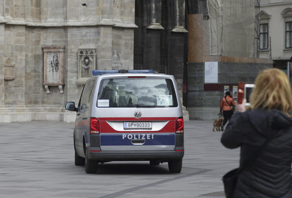 A person holds a mobile device as a police van drives past St. Stephen's cathedral in Vienna, Austria, Wednesday, Mar 15, 2023. Austrian police are warning of a possible “Islamist-motivated attack” targeting churches in Vienna. They cited undisclosed information the country’s intelligence service had received. (AP Photo/Heinz-Peter Bader)