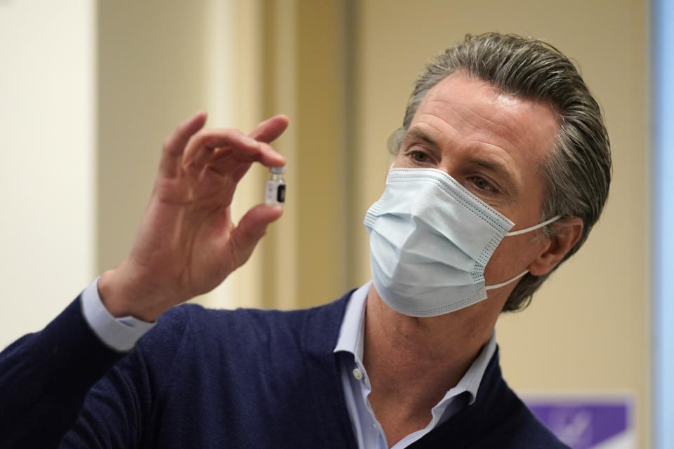 FILE - In this Dec. 14, 2020, file photo, California Gov. Gavin Newsom holds up a vial of the Pfizer-BioNTech COVID-19 vaccine at Kaiser Permanente Los Angeles Medical Center in Los Angeles. When Gov. Newsom provided a dire view of California's out-of-control surge of coronavirus cases and hospitalizations this week, he referred to projection models of future death and misery were becoming "alarmingly" more accurate. If true, then within a month the state's hospitals could be overflowing with 75,000 patients, about five times the current level and an average of 400 people will die every day. (AP Photo/Jae C. Hong, File)