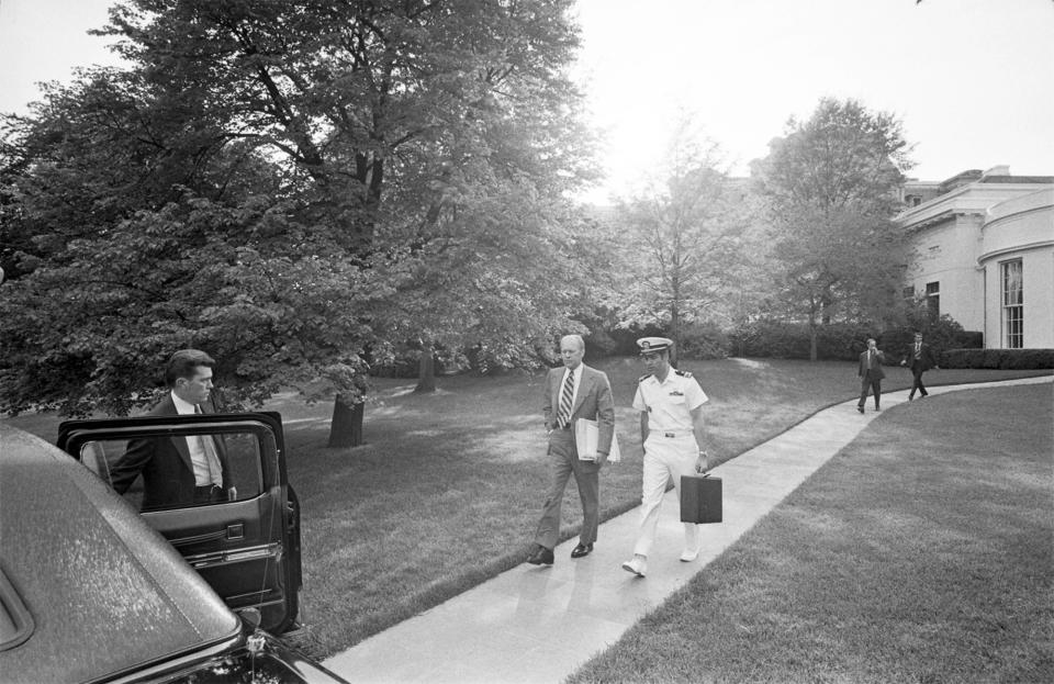 In this photo obtained by the National Security Archive from the Gerald R. Ford Presidential Library, Lt. Commander T. Stephen Todd carries the Presidential Emergency Satchel as he walks with Ford leaving the White House in Washington on May 5, 1975. (Gerald R. Ford Presidential Library/National Security Archive - nsarchive.gwu.edu via AP)