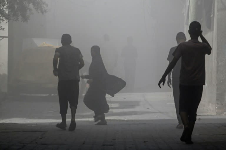 Palestinos caminan entre el humo y el polvo en el campo de Nuseirat, en el centro de la Franja de Gaza, el 8 de junio de 2024 (Bashar TALEB)