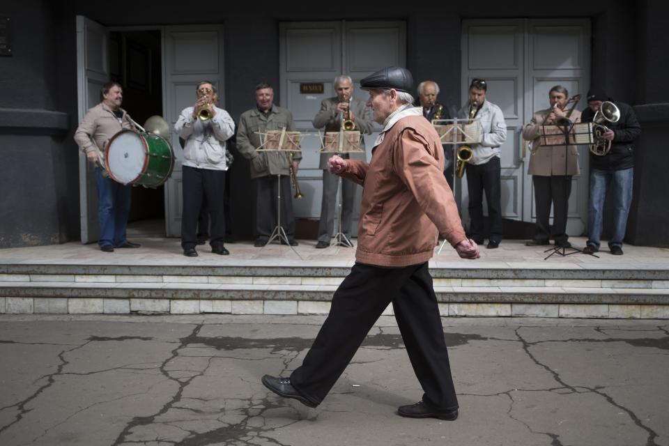 An elderly man marches in front of an amateur band while local citizens gather to mark May Day in Slovyansk, eastern Ukraine, Thursday, May 1, 2014. Russian state news media were quick to dismiss the protests as the work of Ukrainian neo-Nazis, a particularly loaded accusation because Ukrainian nationalists collaborating with the Nazis are blamed for horrific reprisal attacks during World War II. (AP Photo/Alexander Zemlianichenko)