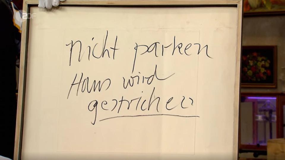 "Nicht parken Haus wird gestrichen", stand da. Schumacher hatte das Blatt Papier einfach als Schild bei der Hausrenovierung verwendet. Lichter war überrascht: "Ach, der hat ein echtes Kunstwerk genommen und hinten drauf geschrieben?" (Bild: ZDF)