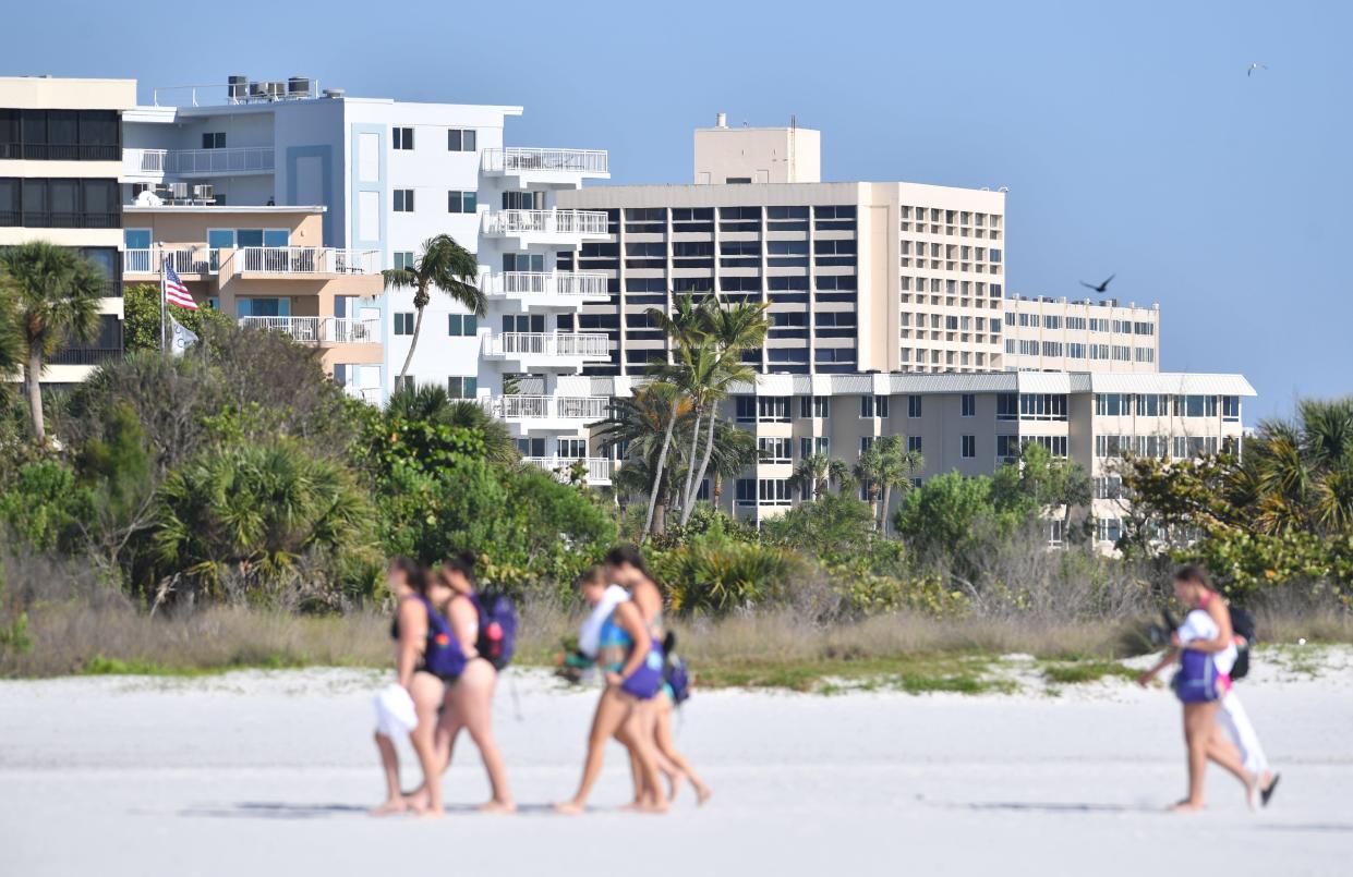 Beachgoers walk past rows of condominiums on Siesta Beach. The Sarasota-Manatee condo market has shifted quickly from a sellers market to a buyers market after insurance rate hikes and increases in condo association fees have doubled over the past two years. Real estate professionals point to increases in inventory, days on market and state legislation following the collapse of the Champlain Towers South condominium in Surfside, Florida as issues contributing to the change.