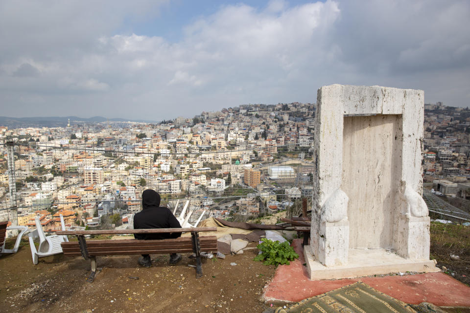 In this Tuesday, Feb. 4, 2020, photo, an Israeli Arab youth sits at a view point overlooking the Israeli Arab town of Umm al-Fahm. President Donald Trump's Mideast initiative suggests that a densely populated Arab region of Israel could be added to a future Palestinian state, if both sides agree. The proposal has infuriated many of Israel's Arab citizens, who view it as a form of forced transfer. (AP Photo/Oded Balilty)