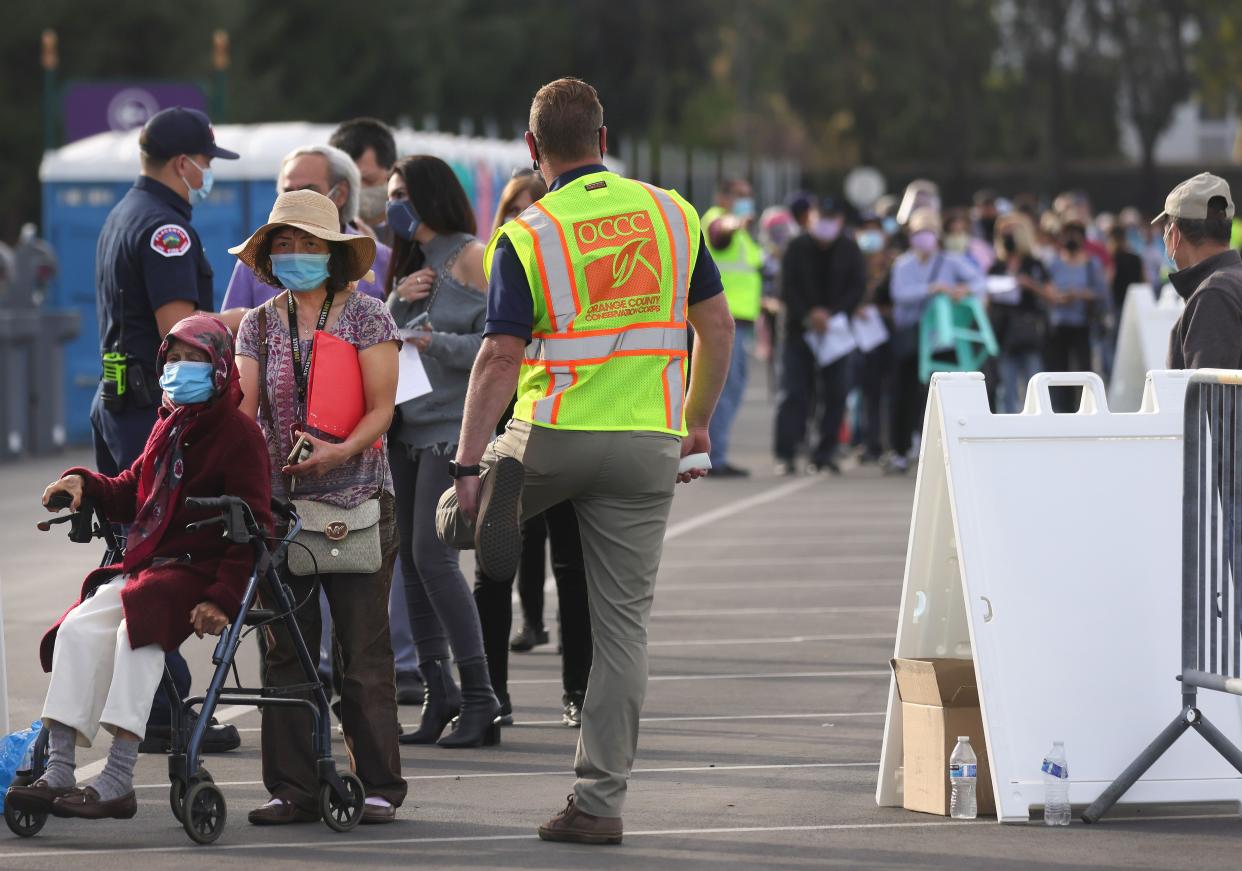 People wait in line to receive the COVID-19 vaccine at a mass vaccination site in a parking lot for Disneyland Resort on Jan. 13, 2021, in Anaheim, Calif.