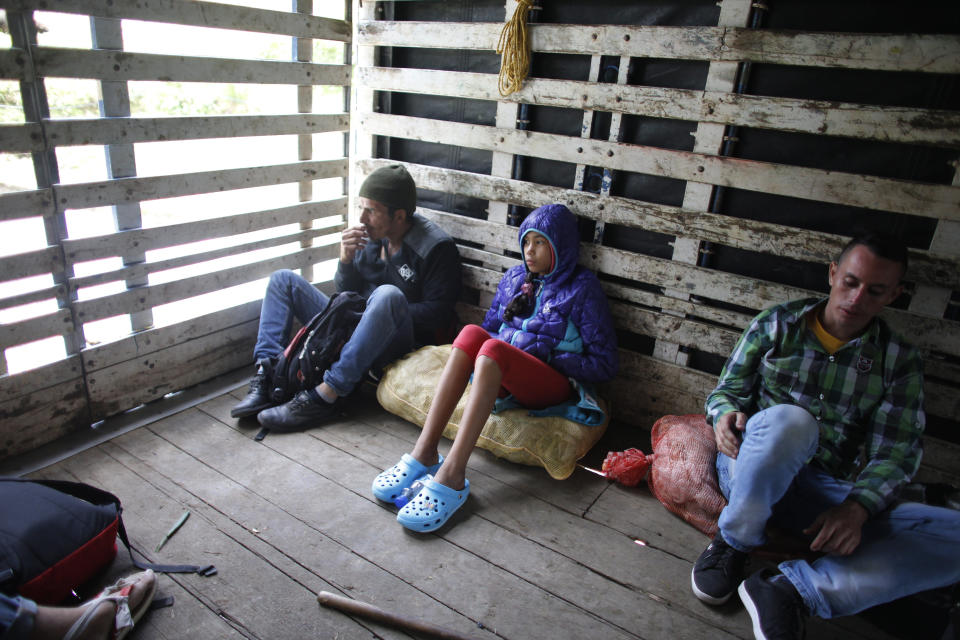 En esta imagen, tomada el 1 de septiembre de 2018, Angelis, de 10 años, se sienta entre otros dos migrantes venezolanos en la parte de atrás de un camión mientras viaja con su madre al Páramo de Berlín, en Colombia, durante su viaje a Perú. Uno de los primeros transportes gratis que tuvieron fue en la parte de atrás de este camión tipo caravana. (AP Foto/Ariana Cubillos)