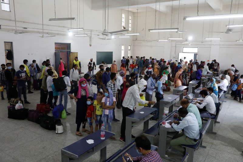 Trabajadores migrantes y sus familias hacen cola para registrarse en los trenes que van a su estado de origen, Uttar Pradesh en Nueva Delhi, India, el 26 de mayo de 2020