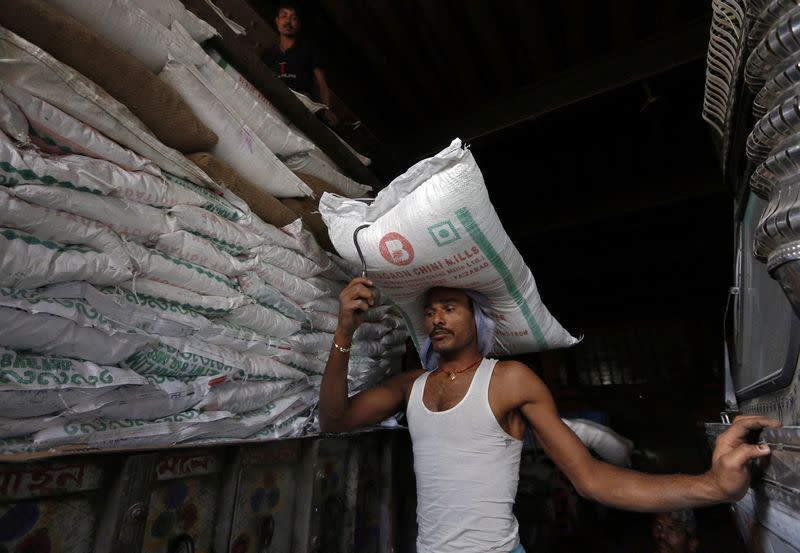 FILE PHOTO: A labourer carries a sack of sugar to load it onto a supply truck in Kolkata, India