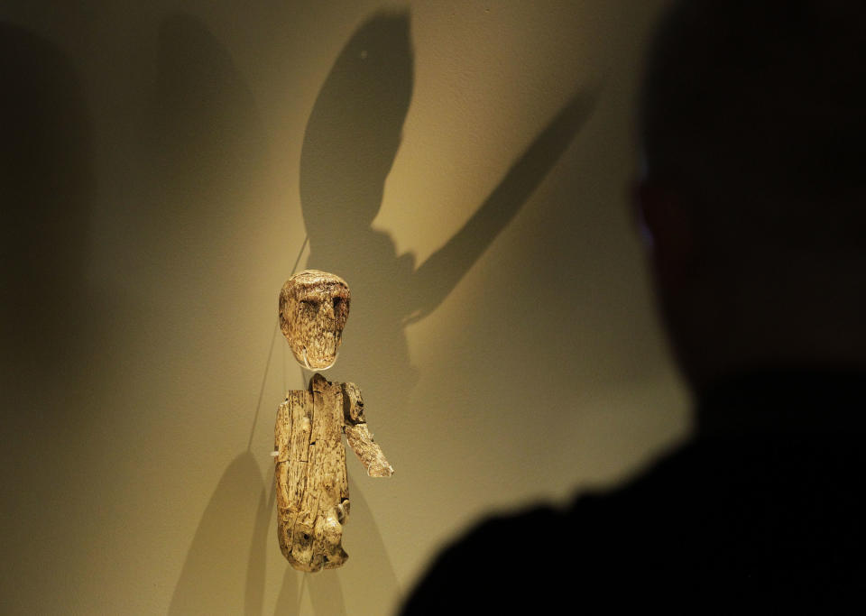 A visitor looks at a small male figure sculptured from a large mammoth tusk dates around 27,000 years ago, discovered at Brno, Moravia, Czech Republic next to a skeleton of a man, on display in an exhibition 'Ice Age Art : arrival of the modern mind' at the British Museum in London, Tuesday, Feb. 5, 2013. The exhibition present masterpieces create from the last Ice Age between 40,000 and 10,000 years ago, drawn from across Europe, by artists with modern minds and presented alongside modern works to illustrate the fundamental human desire to communicate and make art as a way of understanding ourselves and our place in the world. (AP Photo/Sang Tan)