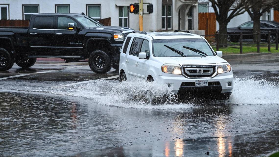 Cars drive through a flooded intersection at Clinton Avenue and Van Ness Boulevard in central Fresno during a heavy downpour in January 2023.
