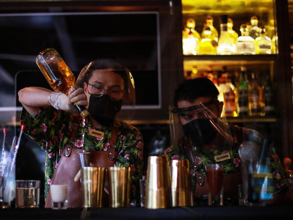 Bartenders with facemasks prepare drinks at the restaurant "Cuerno" on July 03, 2020 in Mexico City, Mexico. As ICU occupancy trends downward, authorities downgraded the alert level from red to orange in Mexico City. Restaurants started a reopening on July 01 with a reduced operation and preventive measures to avoid the spread of Covid-19. (Photo by Manuel Velasquez/Getty Images)