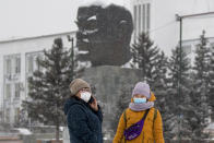 Two women wearing face masks to protect against coronavirus stand in front of a monument of Vladimir Lenin in Ulan-Ude, the regional capital of Buryatia, a region near the Russia-Mongolia border, Russia, Friday, Nov. 20, 2020. Russia’s health care system has been under severe strain in recent weeks, as a resurgence of the coronavirus pandemic has swept the country. (AP Photo/Anna Ogorodnik)