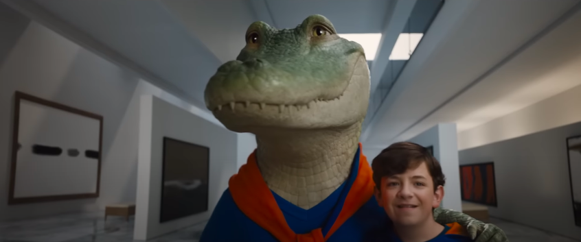 A Crocodile in clothing stands proudly beside a boy