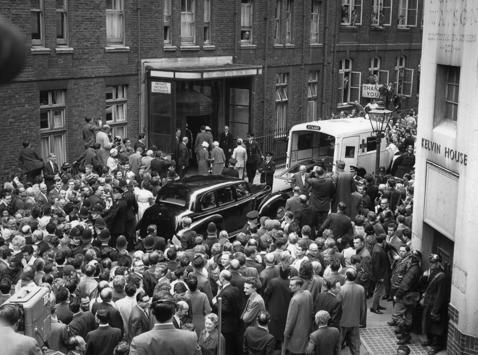 A BBC TV outside broadcast camera (bottom left) records the scene as Sir Winston Churchill is admitted to Middlesex Hospital with a thigh injury, sustained on holiday in Monte Carlo. A group of relatives and officials are seen entering the hospital after Churchill's stretcher had been carried from the ambulance. He was flown home from the South of France by an RAF Aero-Medical Comet jet aircraft.