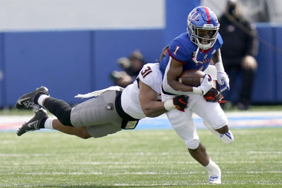 Kansas running back Pooka Williams Jr. (1) is tackled by Oklahoma State safety Kolby Harvell-Peel (31) during the first half of an NCAA college football game in Lawrence, Kan., Saturday, Oct. 3, 2020. (AP Photo/Orlin Wagner)