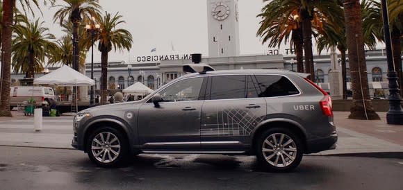 A Volvo SUV with Uber logos and visible self-driving sensor hardware is shown parked in San Francisco.