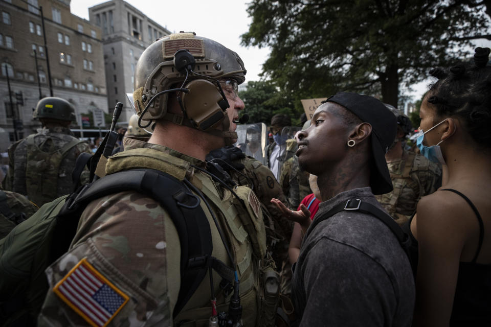 FILE - In this June 3, 2020, file photo, a demonstrator stares at a National Guard soldier as protests continue over the death of George Floyd, near the White House in Washington, D.C. Reports of hateful and violent speech on Facebook poured in on the night of May 28 after President Donald Trump hit send on a social media post warning that looters who joined protests following Floyd's death last year would be shot, according to internal Facebook documents shared with The Associated Press. (AP Photo/Alex Brandon, File)