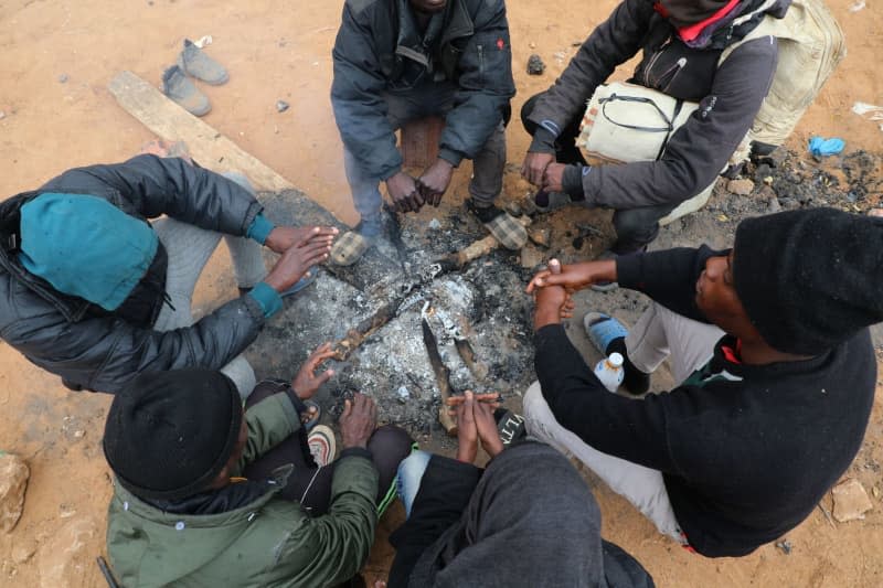 Migrants from Sub-Saharian Africa gather around a fire at a camp in Jebeniana. Khaled Nasraoui/dpa