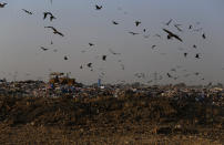 In this Tuesday, Dec. 4, 2018 photo crows and black kites fly next to a tractor working on a garbage-dump on the outskirts of Islamabad, Pakistan. As politicians haggle at a U.N. climate conference in Poland over ways to limit global warming, the industries and machines powering our modern world keep spewing their pollution into the air and water. The fossil fuels extracted from beneath the earth’s crust _ coal, oil and gas _ are transformed into the carbon dioxide that is now heating the earth faster than scientists had expected even a few years ago. (AP Photo/Anjum Naveed)