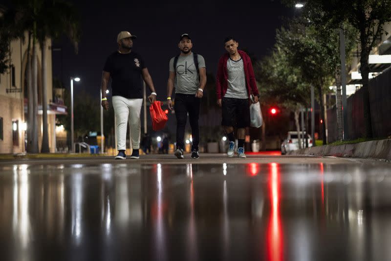 José Manuel (derecha), solicitante de asilo venezolano, camina con otros migrantes mientras espera un autobús para Chicago, en el centro de Brownsville, Texas
