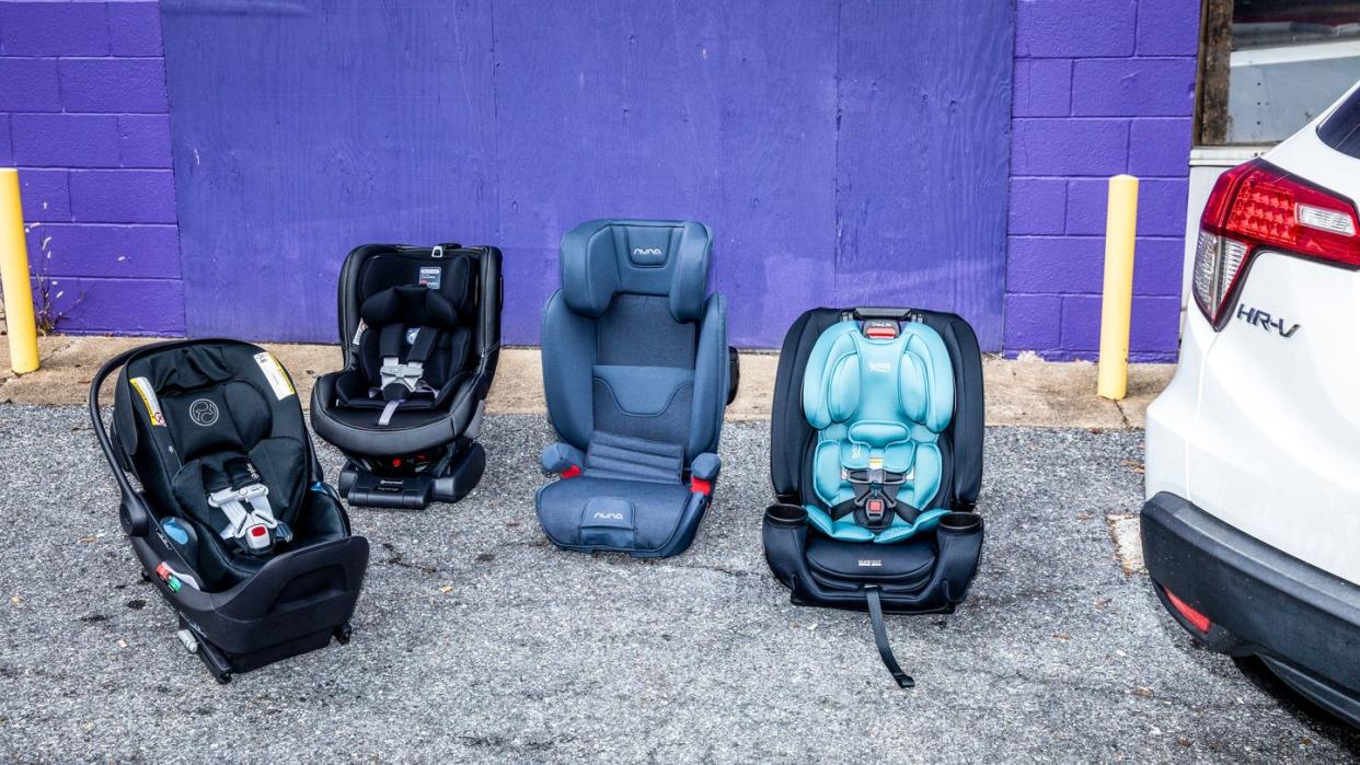 four car seats on the ground next to a car