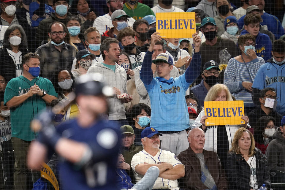 FILE - Seattle Mariners' fans hold up signs reading "Believe" as Mariners' Mitch Haniger comes to bat in the sixth inning of a baseball game on Oct. 2, 2021, in Seattle. Even if baseball’s first work stoppage in 26 years doesn’t result in missed games, the league and its players are at risk of alienating their next wave of fans. (AP Photo/Elaine Thompson, File)