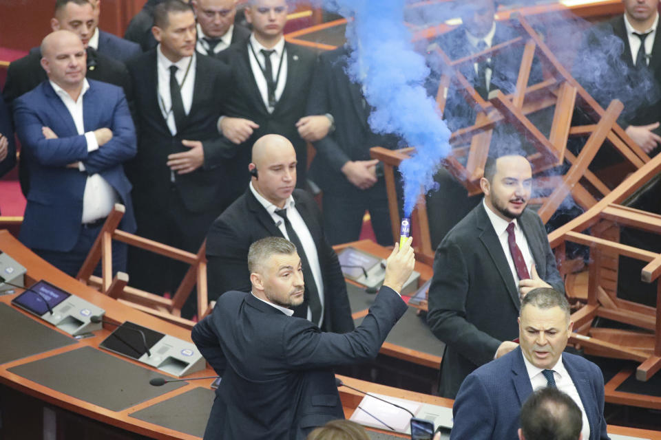 Bledion Nallbati, Democratic lawmaker, holds a flare during a parliament session in Tirana, Albania, Thursday Dec. 7, 2023. The Albanian Parliament on Thursday passed the annual budget and other draft laws in a disrupted vote from the opposition using flares and noise to protest against what they consider as an authoritarian rule from the governing Socialist Party. (AP Photo/Armando Babani)