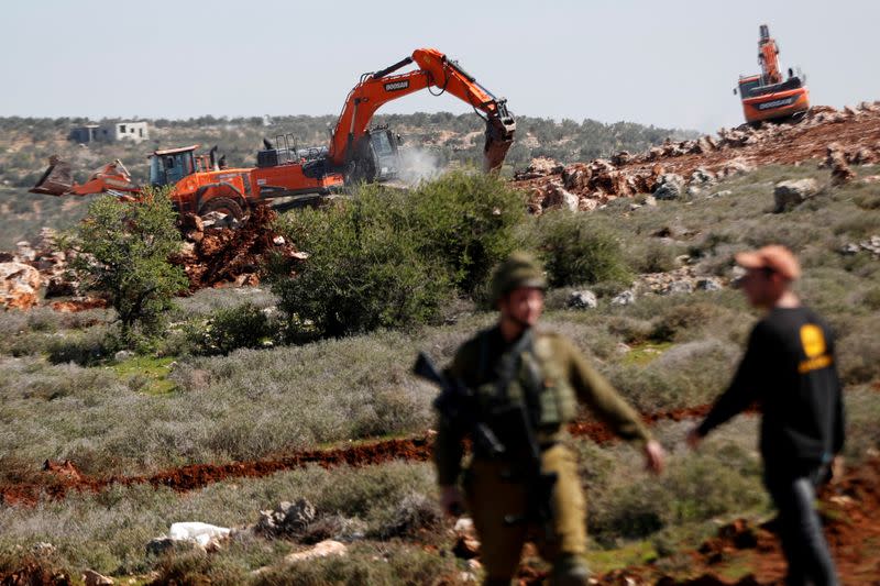 Israeli machineries, guarded by Israeli forces, bulldoze lands near the Palestinian village of Qusra, in the Israeli occupied West Bank